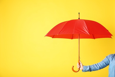 Photo of Woman holding modern colorful umbrella on yellow background, closeup. Space for text