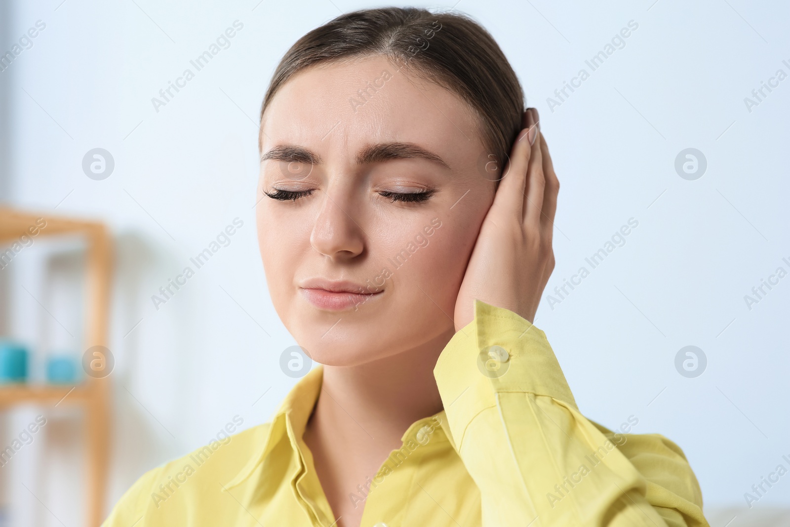 Photo of Young woman suffering from ear pain indoors