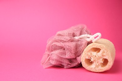 Shower puff and natural loofah sponge on pink background, space for text