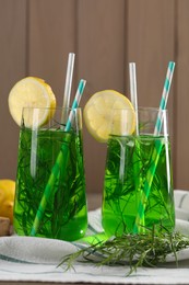 Glasses of refreshing tarragon drink with lemon slices on table