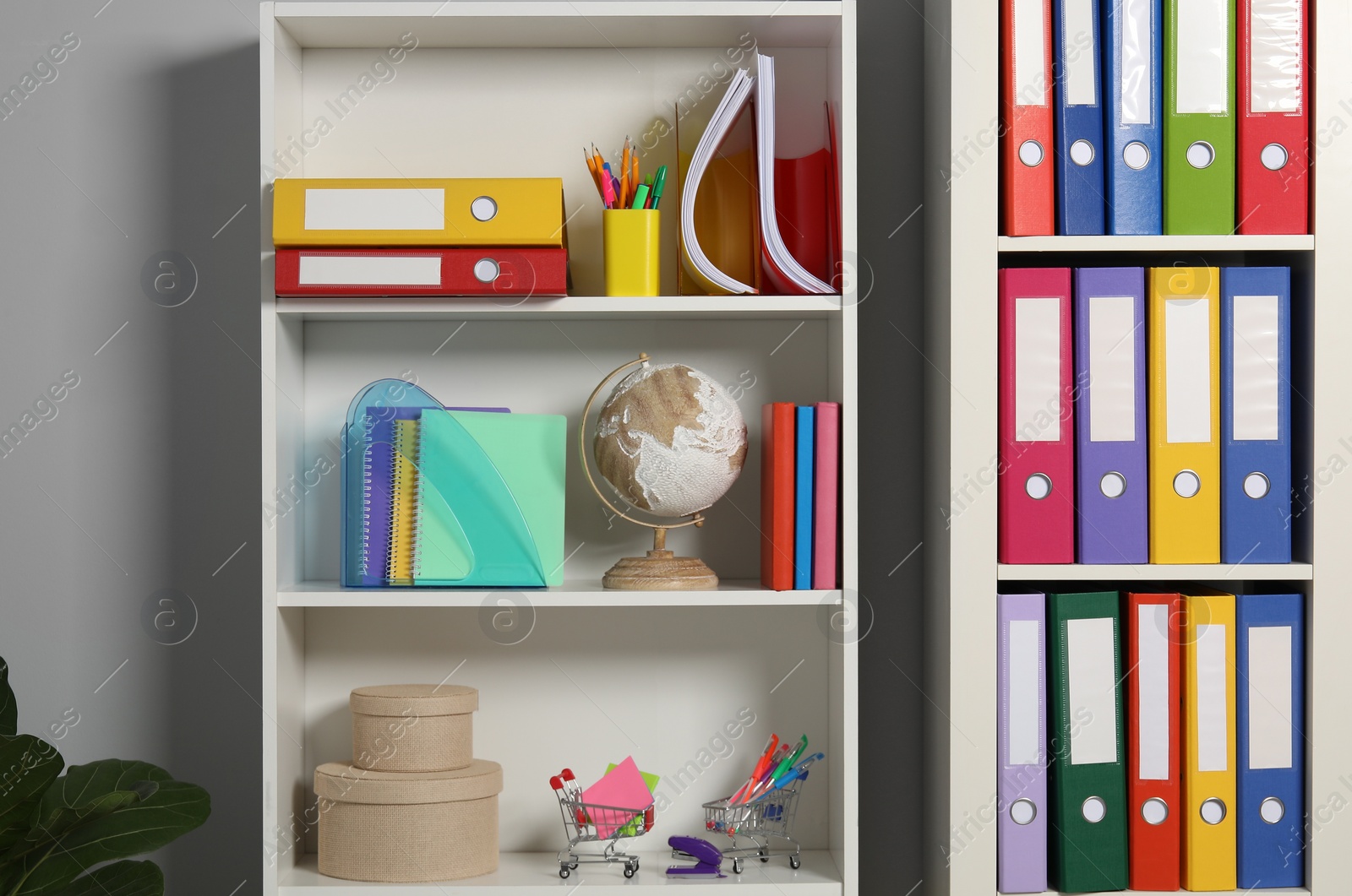 Photo of Colorful binder office folders and other stationery on shelving unit indoors