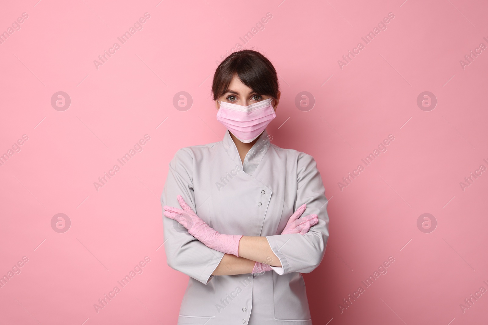 Photo of Cosmetologist in medical uniform on pink background