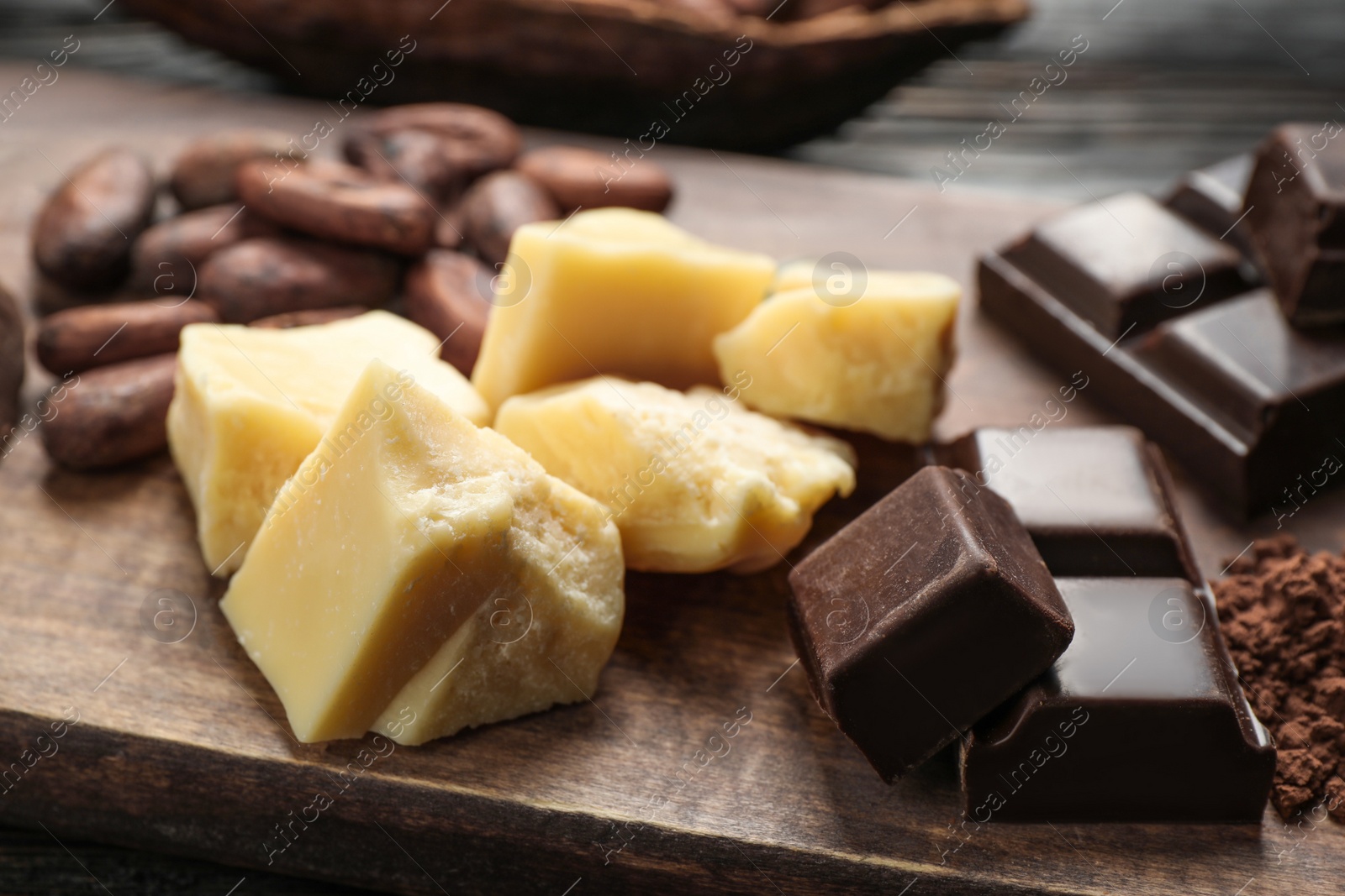 Photo of Organic cocoa butter and chocolate on wooden table, closeup