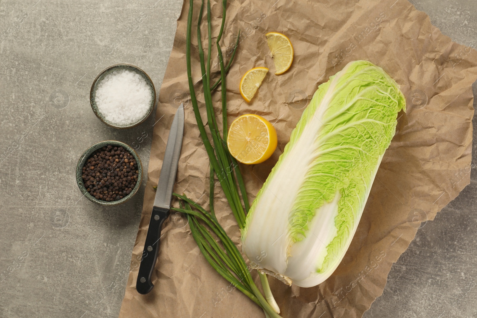 Photo of Fresh Chinese cabbage, lemon, green onion and spices on light grey table, flat lay