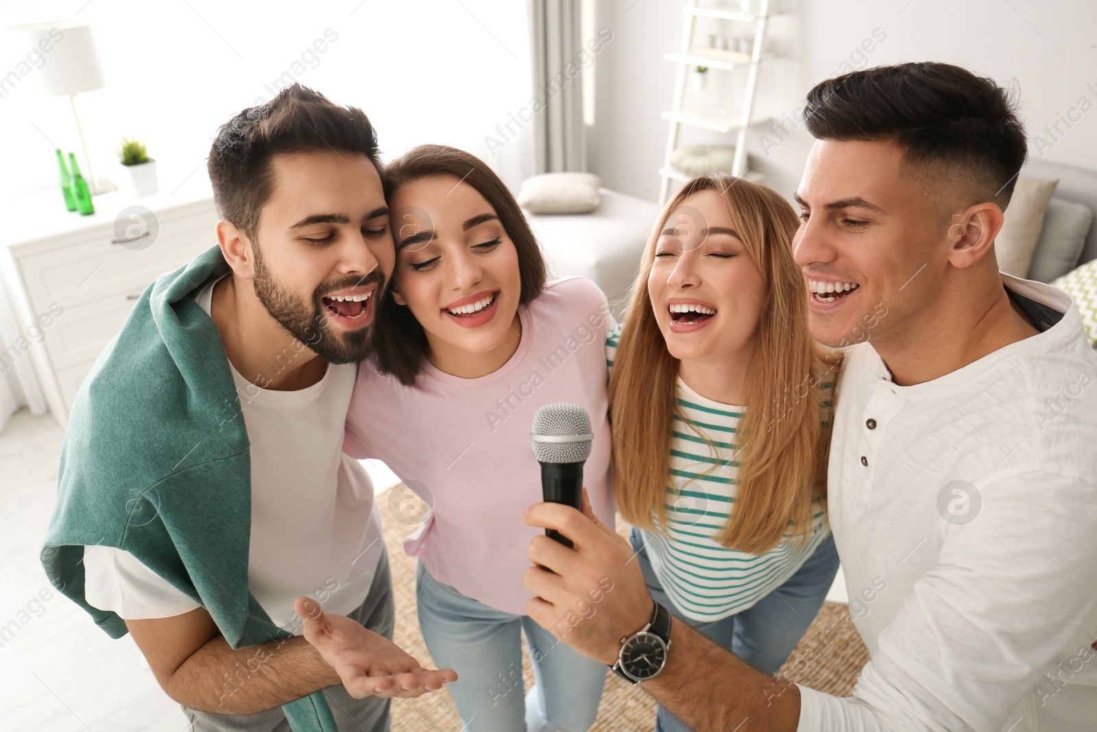 Photo of Happy friends singing karaoke together at home