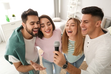 Happy friends singing karaoke together at home