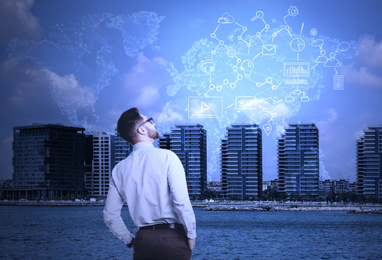 Image of Young businessman with world map and network schemes against cityscape. Cloud technology 