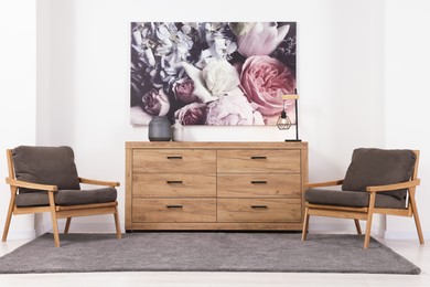 Photo of Stylish living room with wooden chest of drawers, armchairs and beautiful picture. Interior design