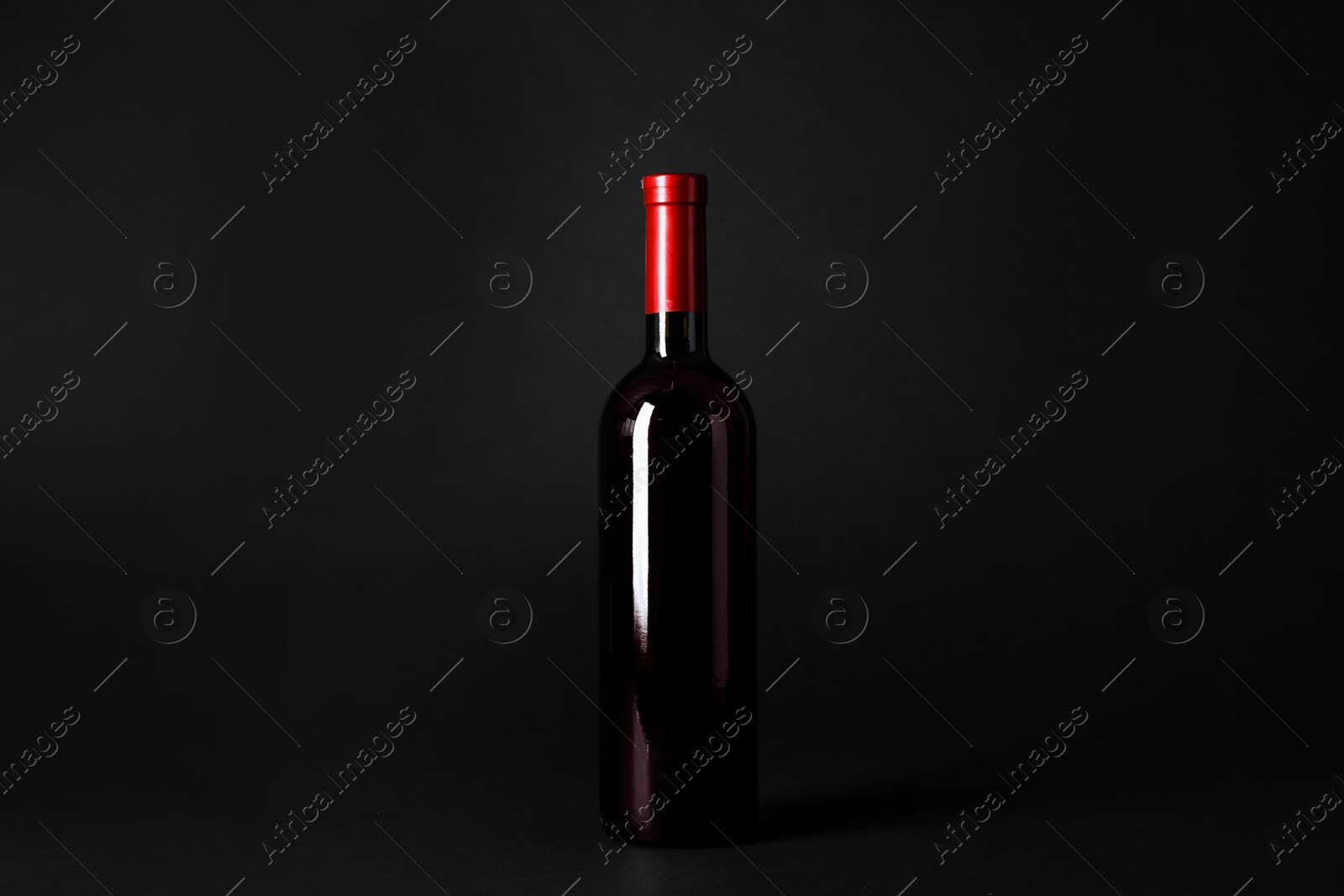 Photo of Bottle of expensive red wine on dark background
