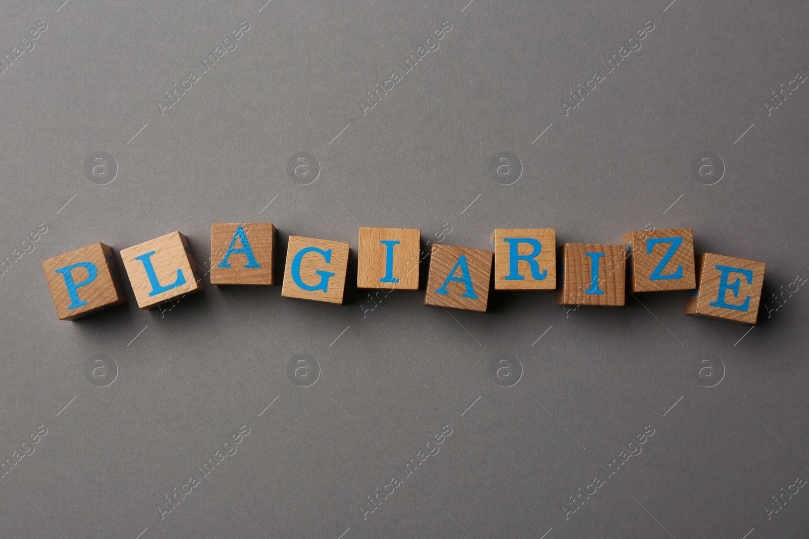 Photo of Wooden cubes with word Plagiarism on grey background, flat lay