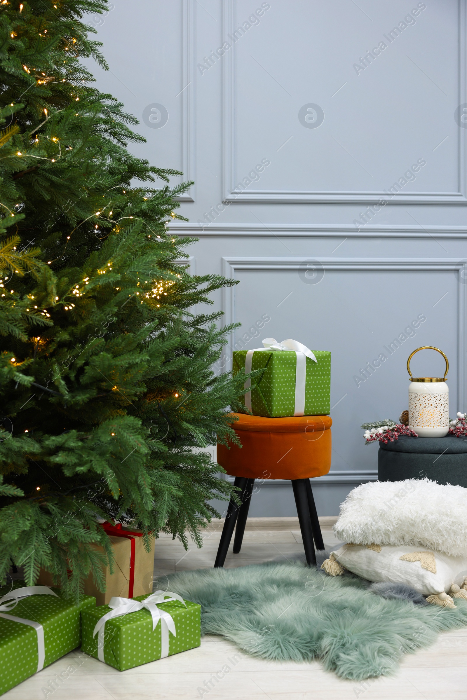 Photo of Beautiful Christmas tree decorated with festive lights and many gift boxes in room