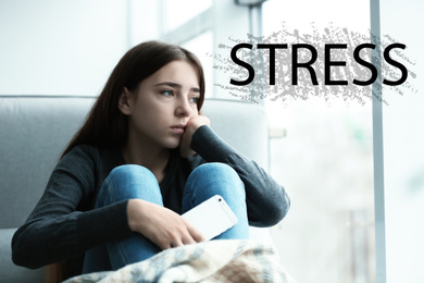 Image of Word STRESS and depressed young girl sitting at window indoors