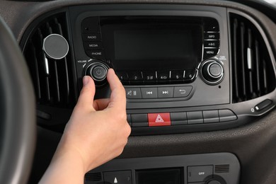 Photo of Listening to radio while driving. Woman turning volume button on vehicle audio in car, closeup