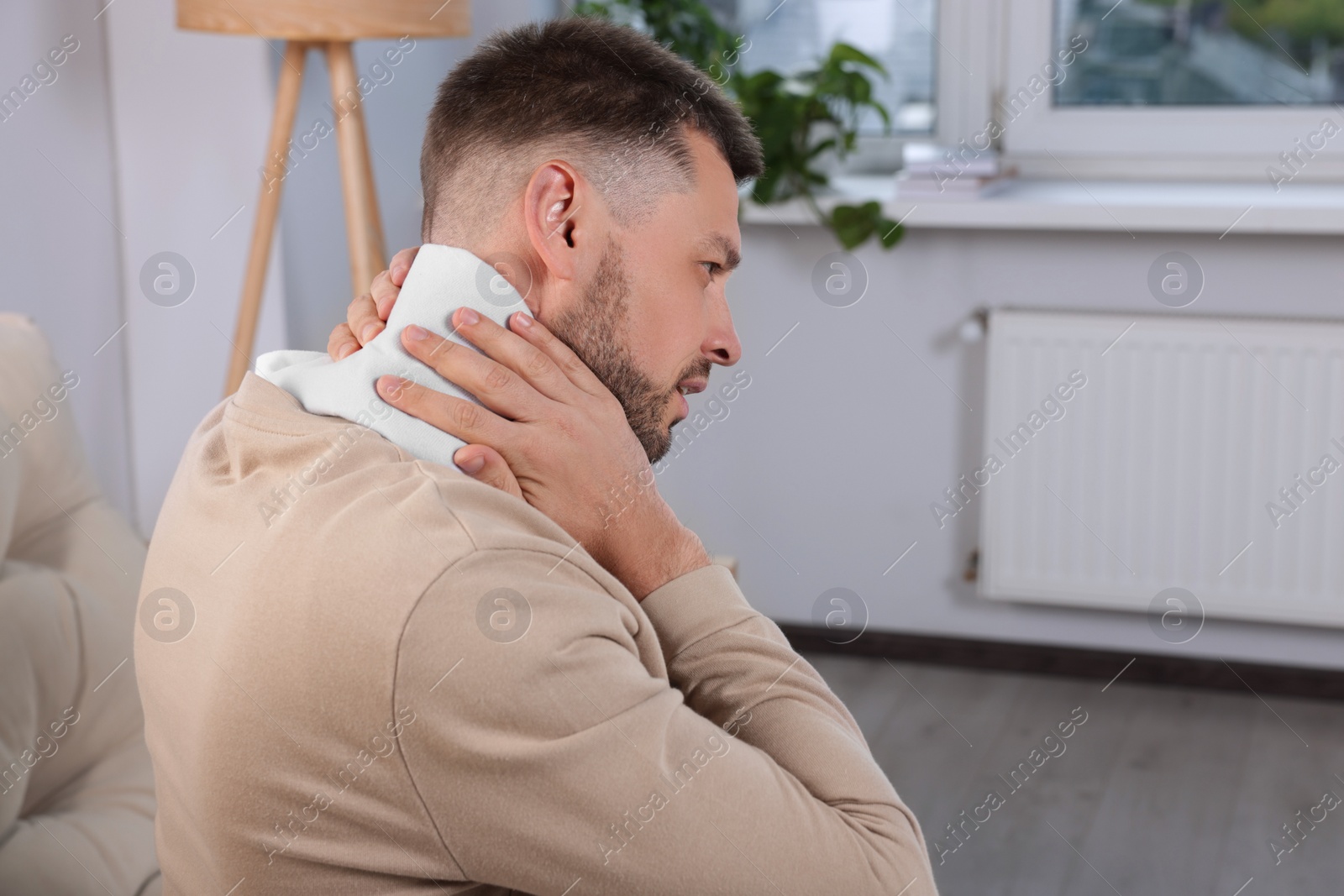 Photo of Man using heating pad at home, space for text