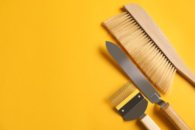 Photo of Beekeeping tools on yellow background, flat lay. Space for text