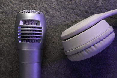 Photo of Microphone and headphones on grey textured background, flat lay. Sound recording and reinforcement