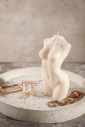 Beautiful female body shape candle and accessories on grey table