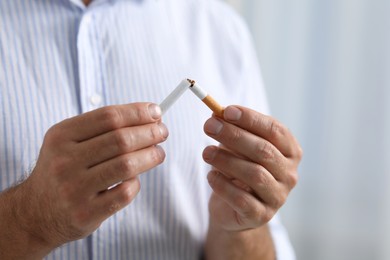 Photo of Stop smoking concept. Man breaking cigarette on light background, closeup