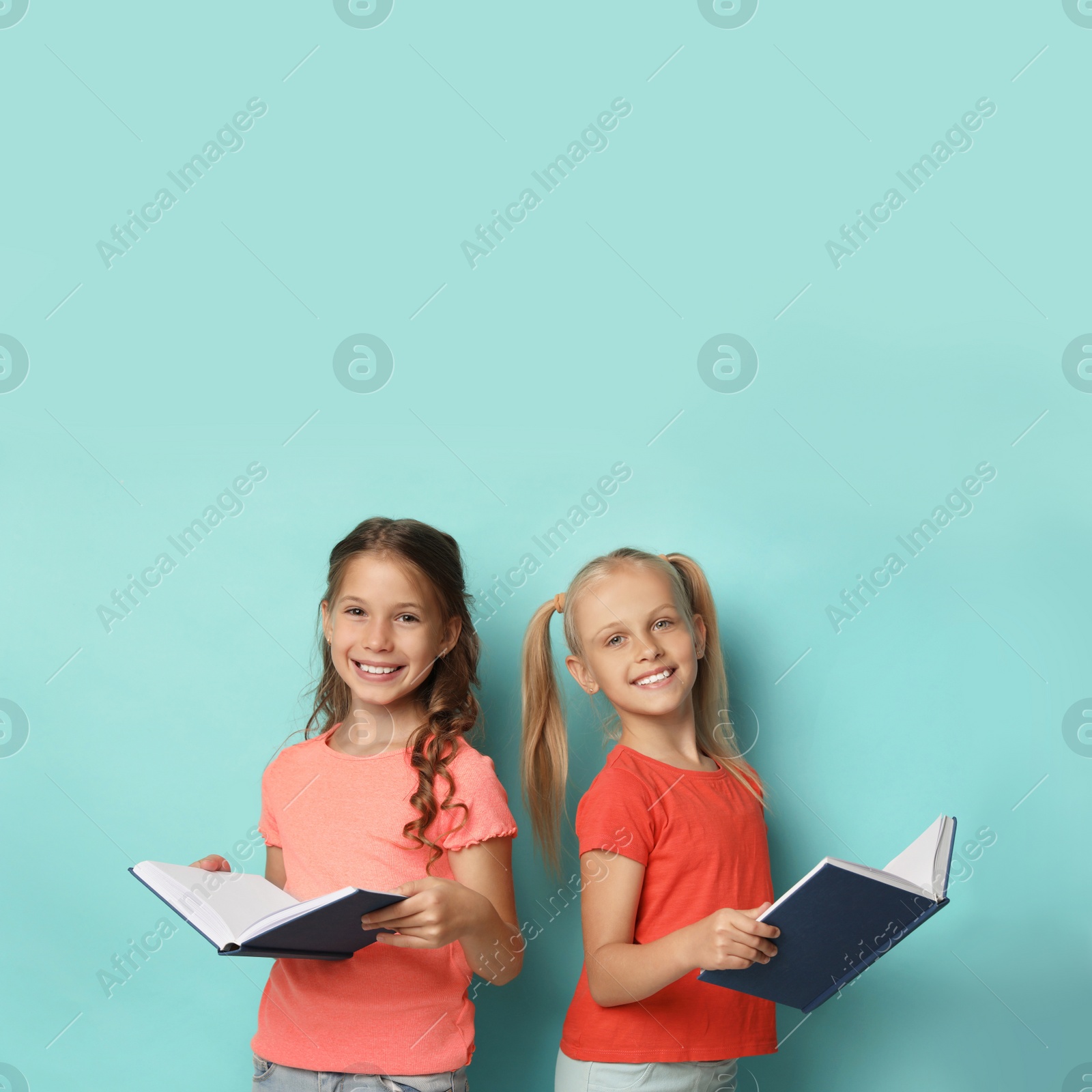 Photo of Portrait of little girls reading books on turquoise background