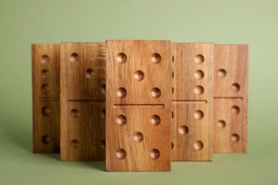 Photo of Wooden domino tiles with pips on green background
