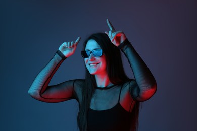 Photo of Portrait of beautiful young woman with sunglasses on color background