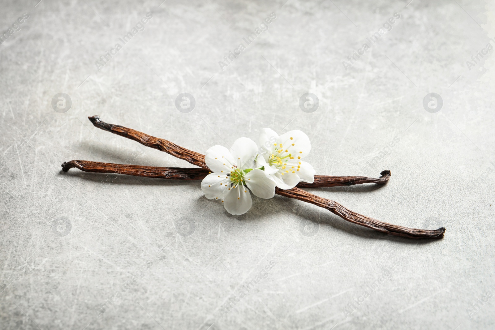 Photo of Vanilla sticks and flowers on grey background