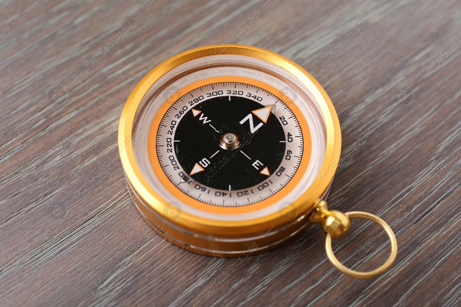 Photo of One compass on wooden table, closeup. Navigation equipment