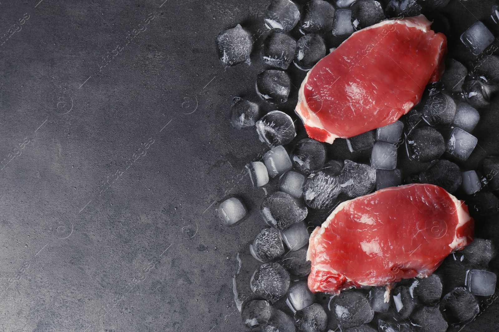 Photo of Flat lay composition with raw meat, ice cubes and space for text on dark background