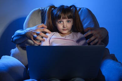Stranger reaching little child with laptop on color background. Cyber danger