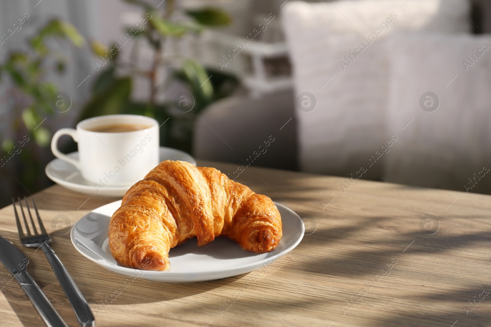 Photo of Delicious fresh croissant served with coffee on wooden table. Space for text