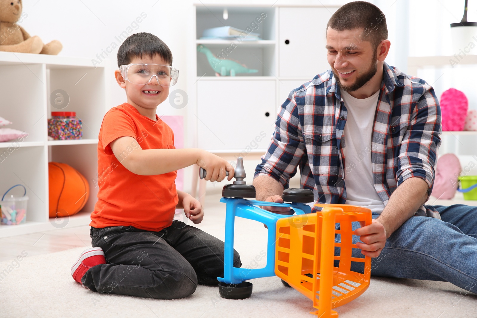 Photo of Man and his child as repairman playing with toy cart at home