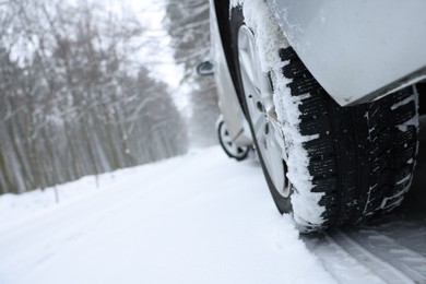 Photo of Car with winter tires on snowy road in forest, closeup. Space for text