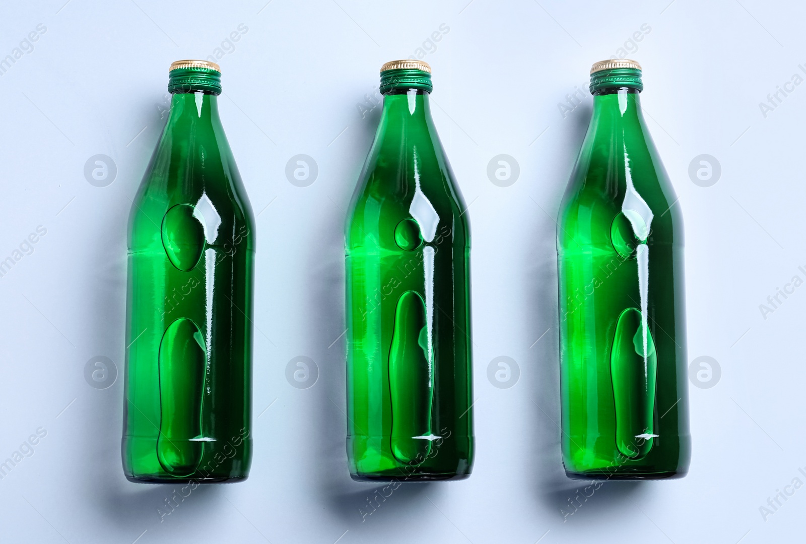 Photo of Glass bottles with water on white background, flat lay