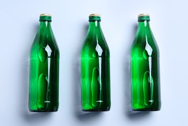 Glass bottles with water on white background, flat lay