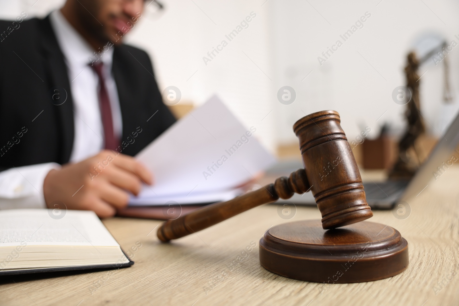 Photo of Lawyer working with document at table in office, focus on gavel