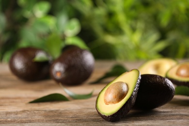 Photo of Whole and cut avocados on wooden table. Space for text