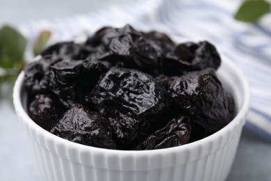 Photo of Sweet dried prunes in bowl on table, closeup