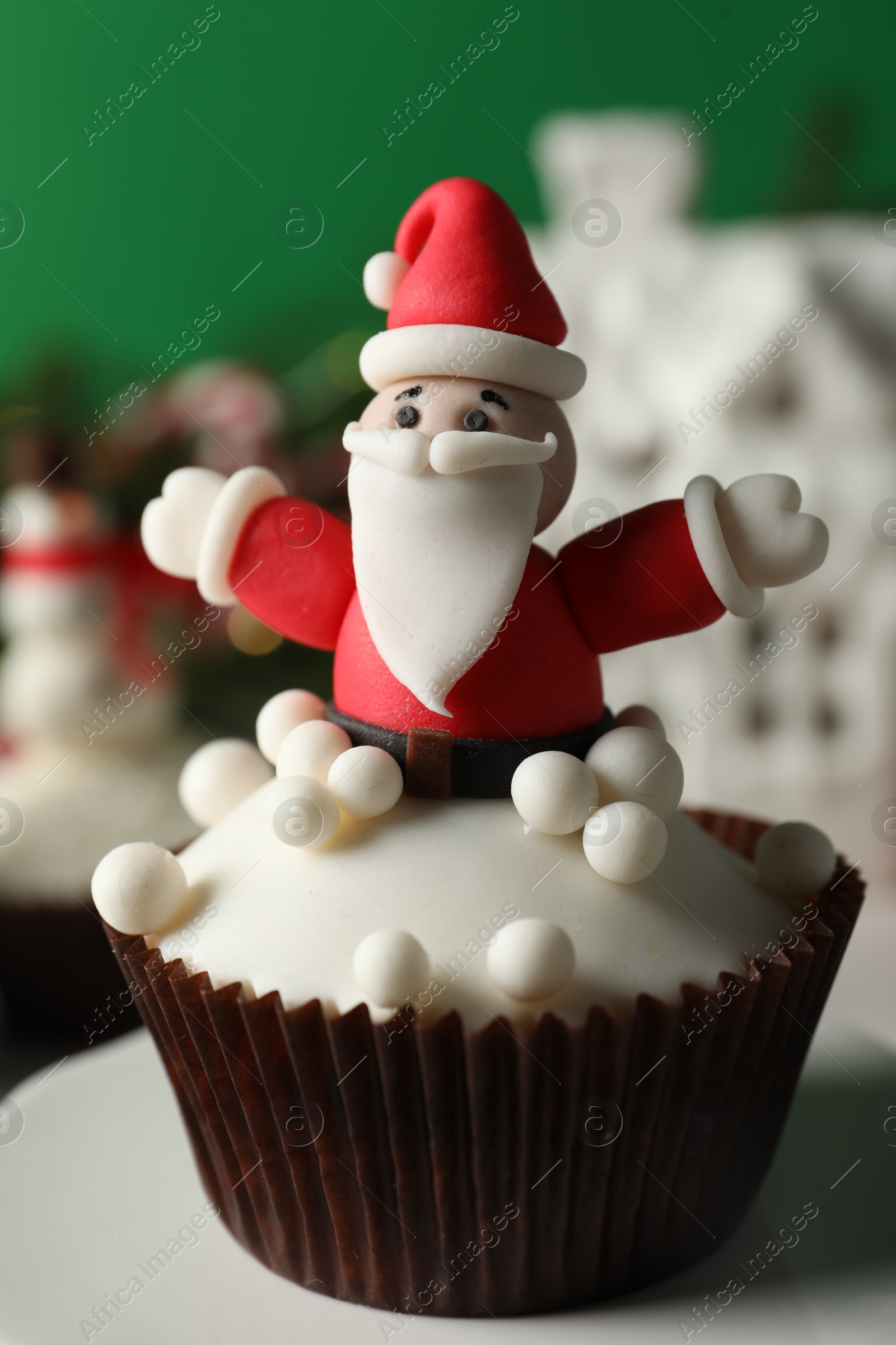 Photo of Tasty Christmas cupcake with Santa Claus figure on table, closeup