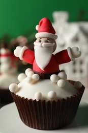 Photo of Tasty Christmas cupcake with Santa Claus figure on table, closeup