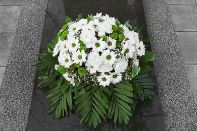 Photo of Funeral wreath of flowers on granite tombstone outdoors, above view