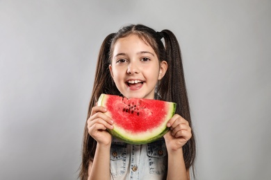 Photo of Cute little girl with watermelon on grey background