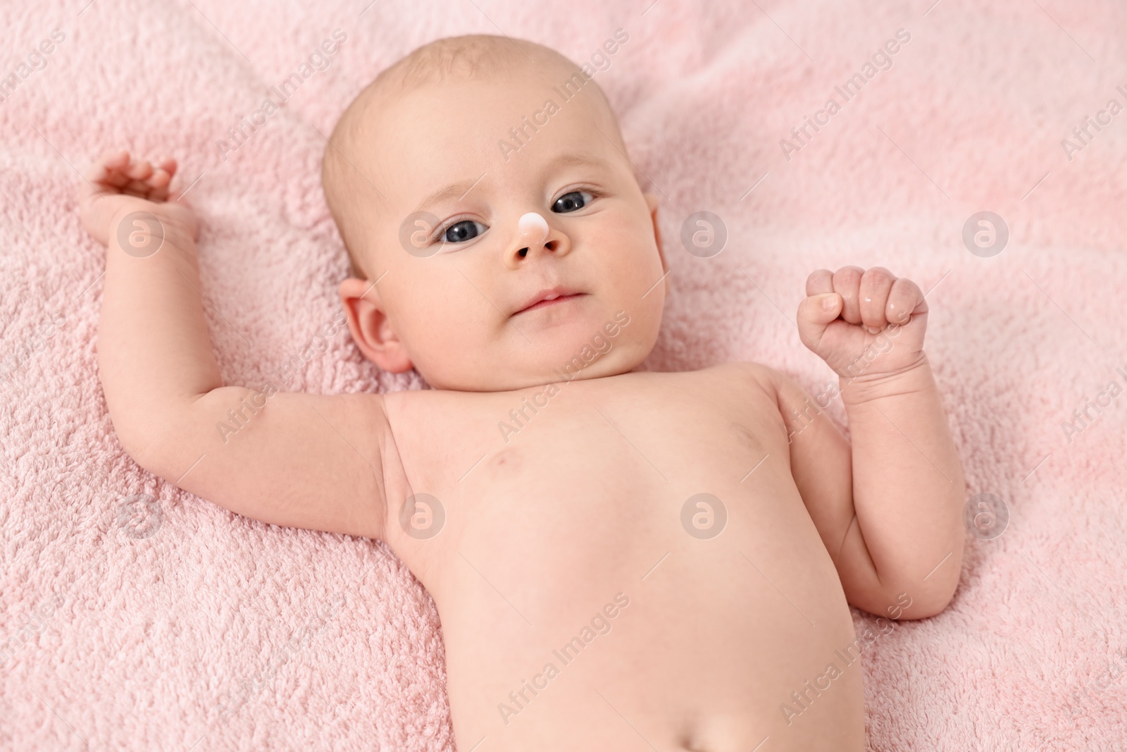 Photo of Cute little baby with cream on nose on pink blanket, above view