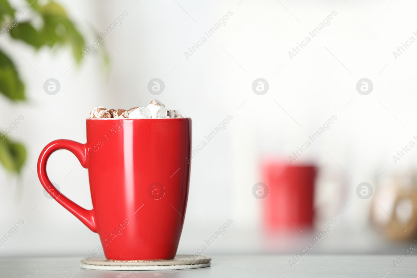 Photo of Cup of tasty cocoa with marshmallows on table indoors. Space for text