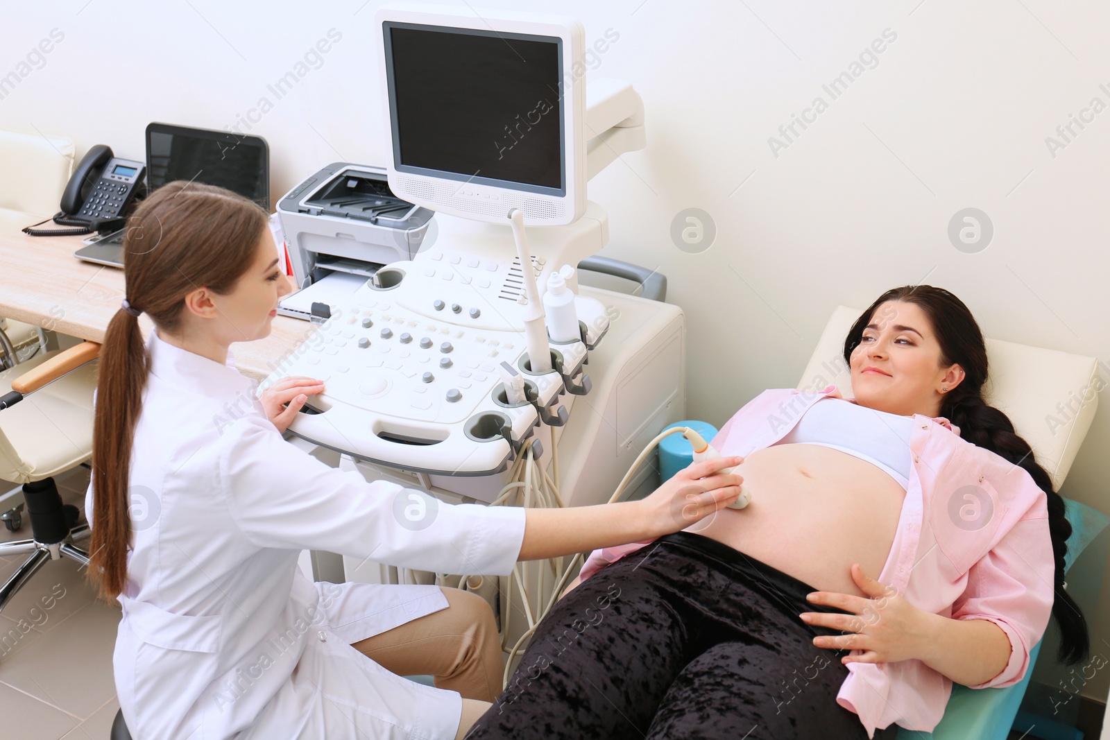 Photo of Young pregnant woman undergoing ultrasound scan in clinic