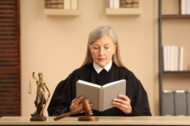 Judge reading book at wooden table indoors