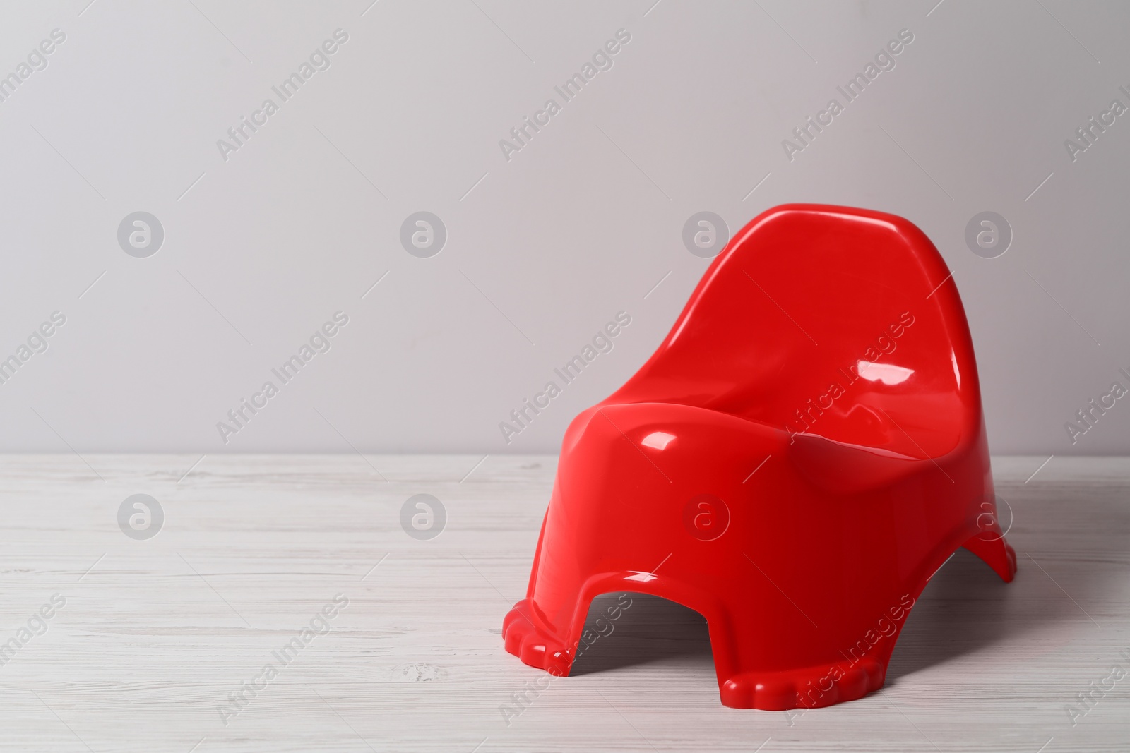 Photo of Red baby potty near light wall, space for text. Toilet training