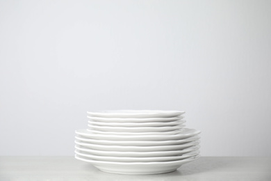 Photo of Stack of clean plates on table against white background. Space for text