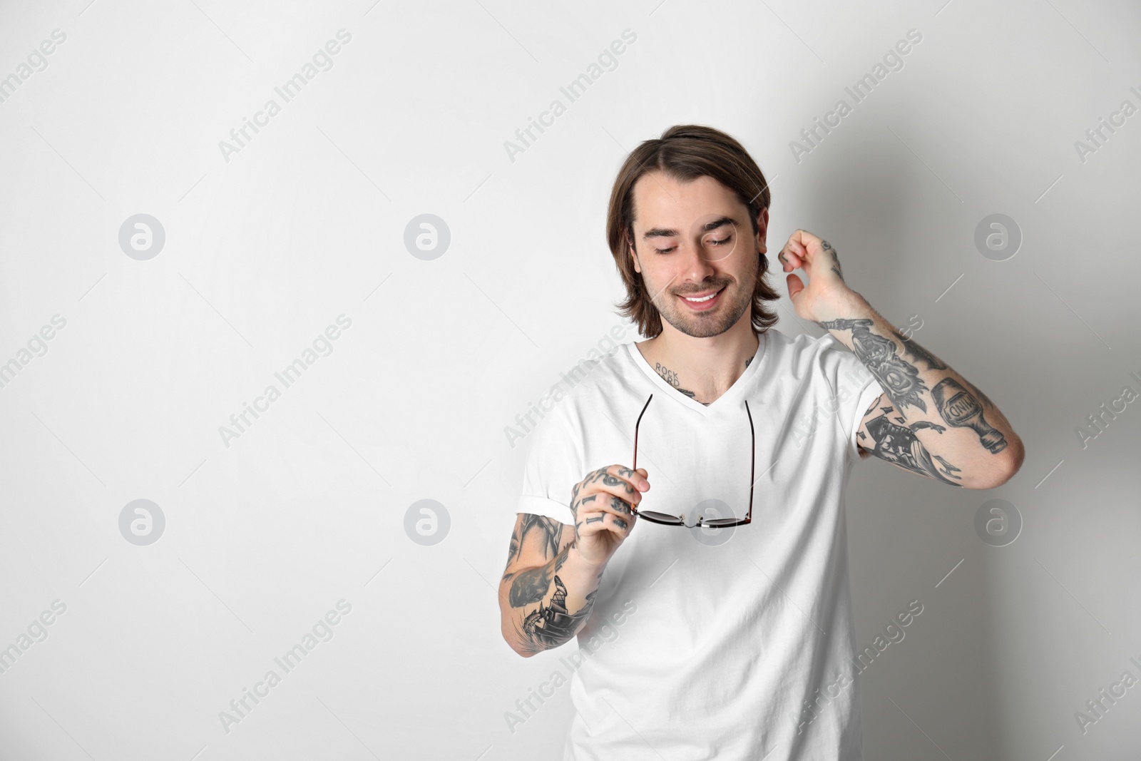 Photo of Young man with tattoos on arms against white background