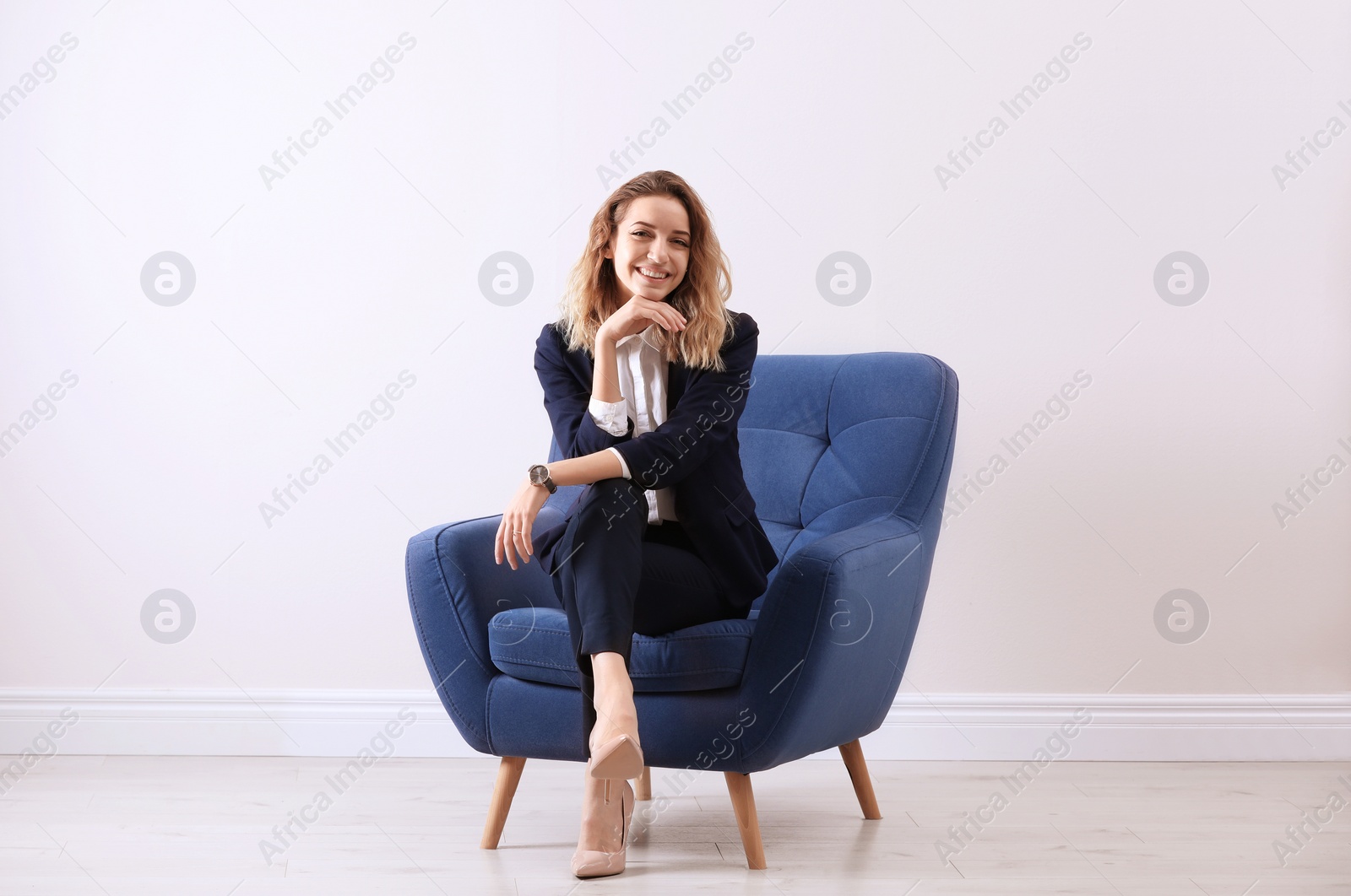 Photo of Beautiful young woman sitting in armchair indoors