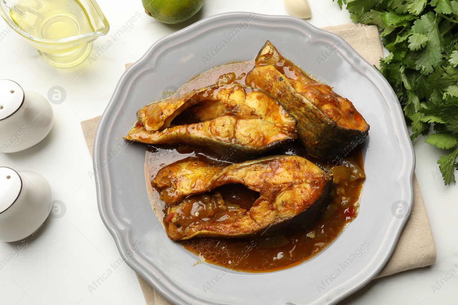 Photo of Tasty fish curry and ingredients on white marble table, flat lay. Indian cuisine